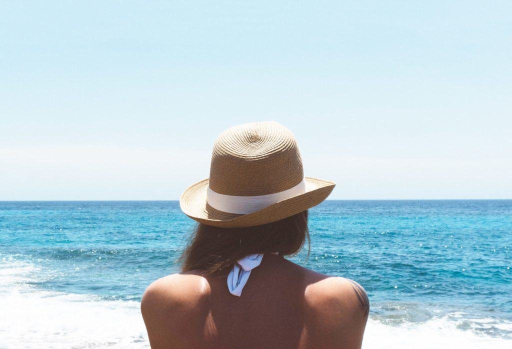 Head and shoulders of women wearing a hat facing the sea