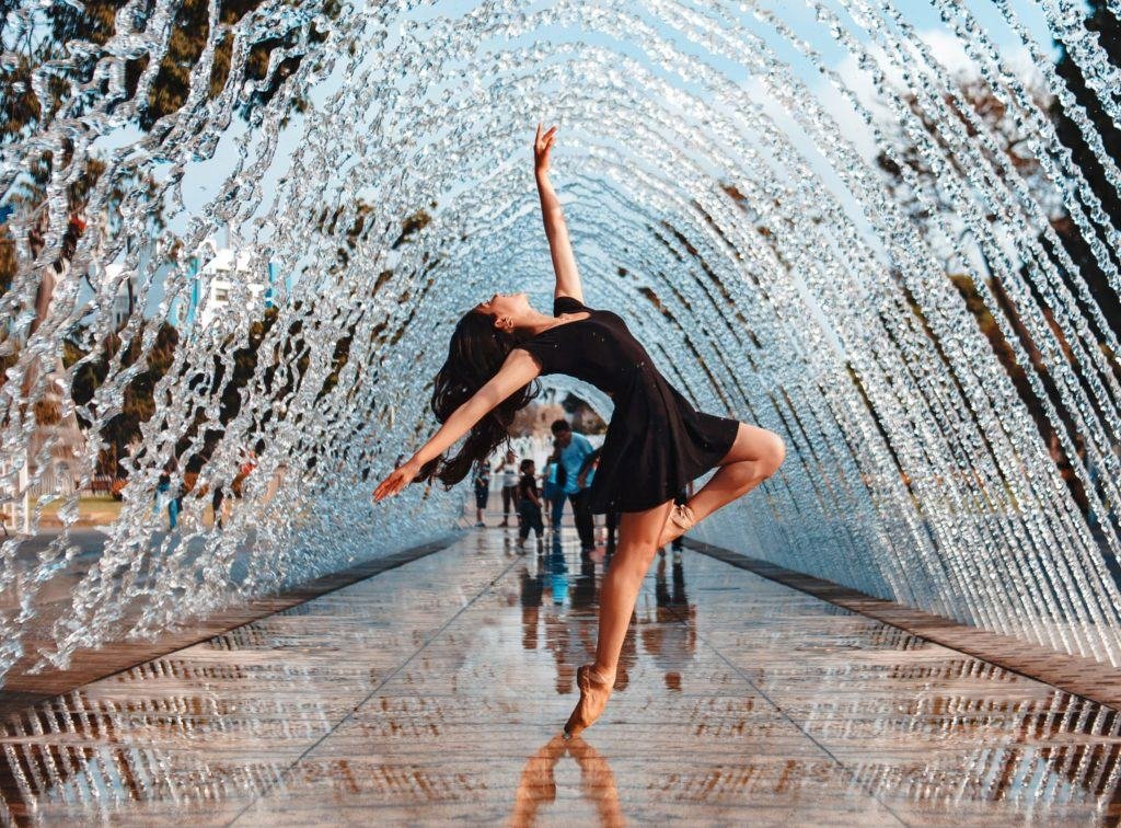 a woman dancing under a fountain